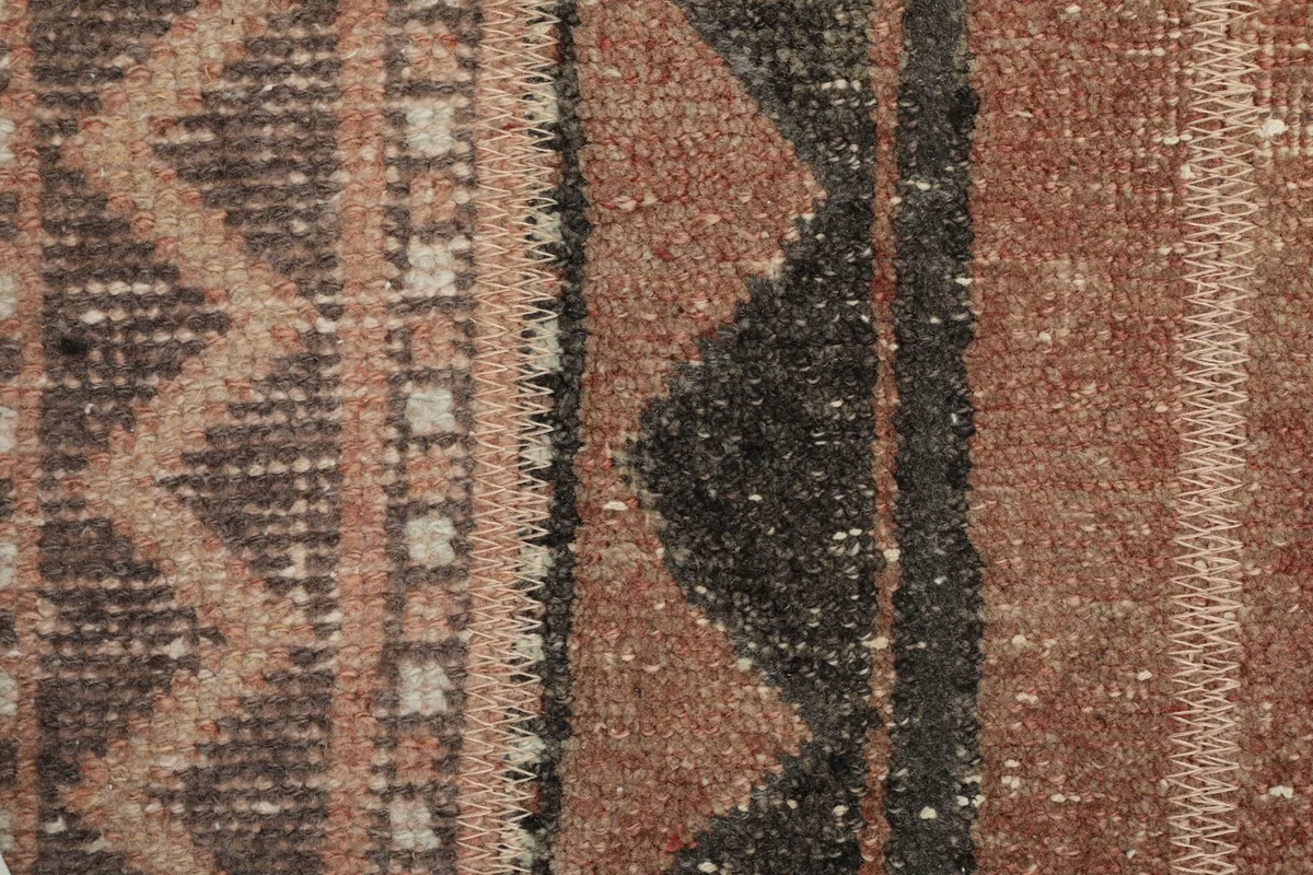 Extreme close-up showing the low wool pile texture and knotting detail in rust, brown, and black.