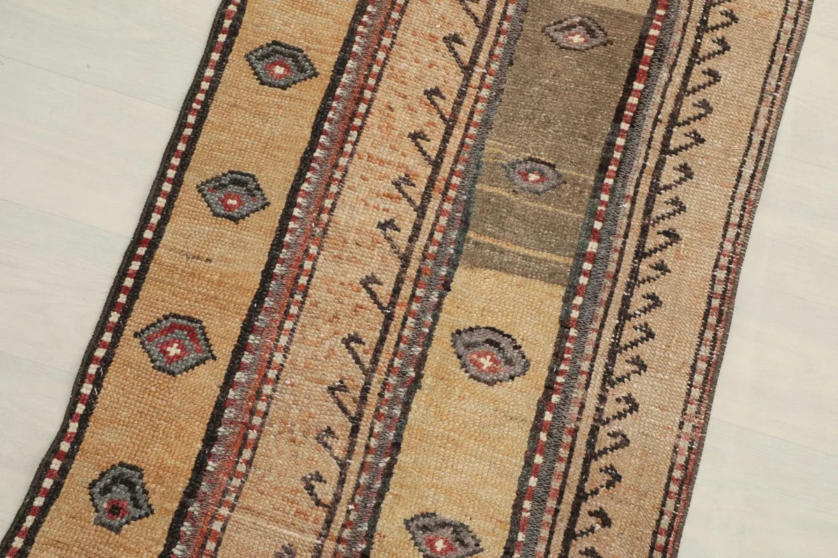 Close-up detail of the rug's central design, highlighting the tan and brown stripes with red and gray geometric