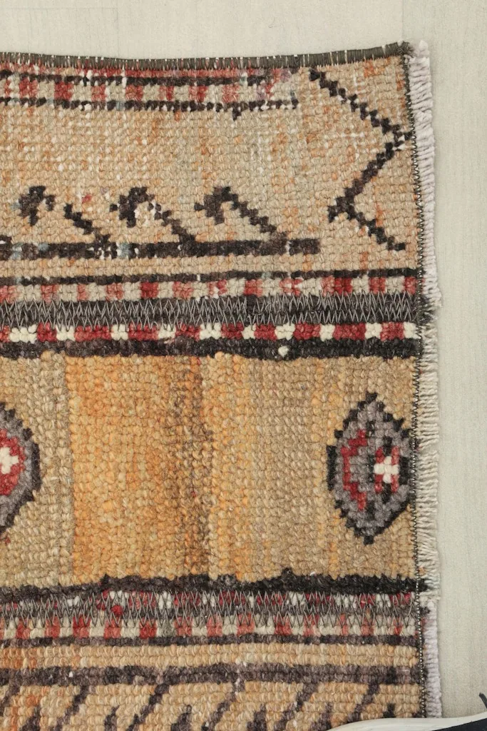 Close view of a corner of the rug, revealing the craftsmanship and the slight wear consistent with its vintage age.