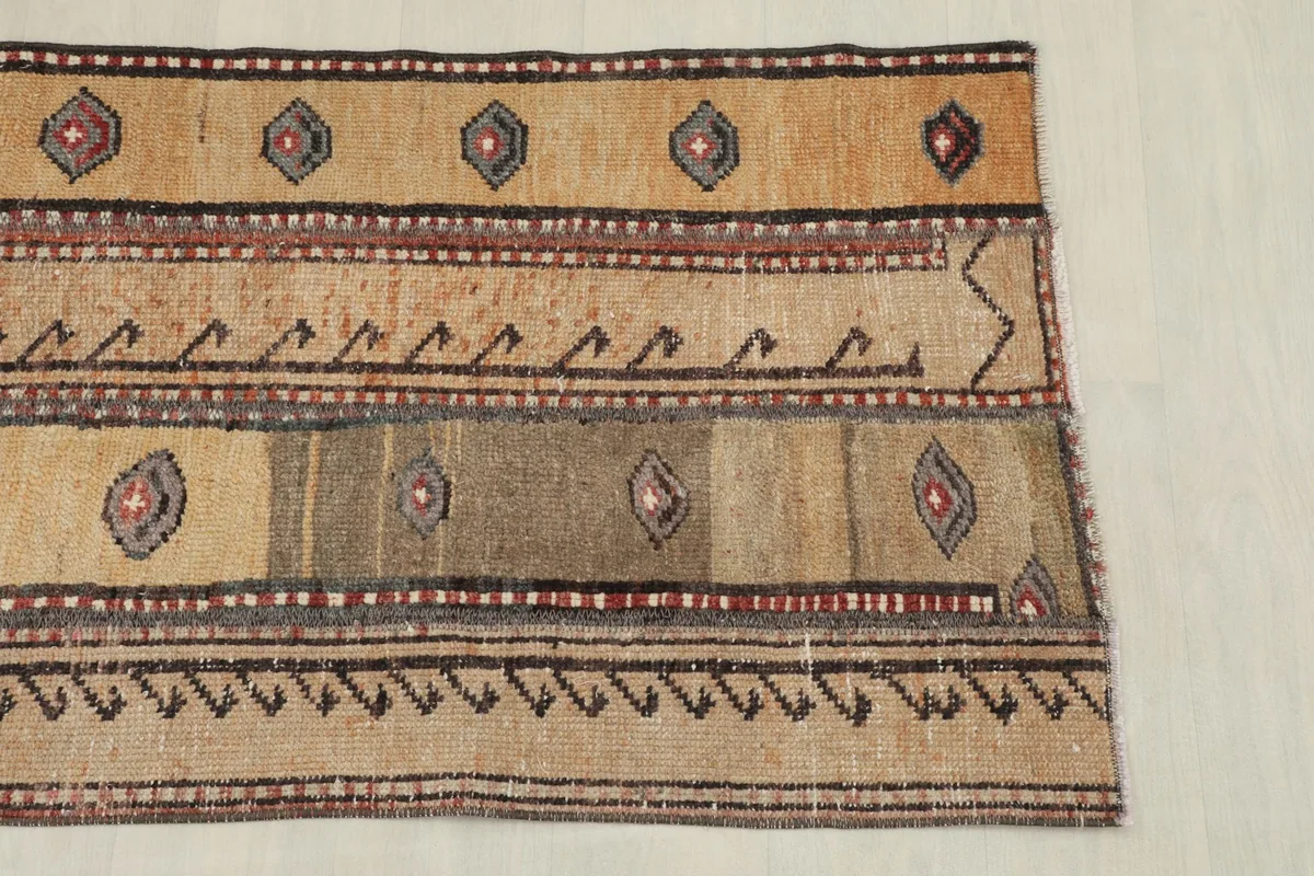 Section of the rug showing a border design with black and red geometric elements on a tan background.