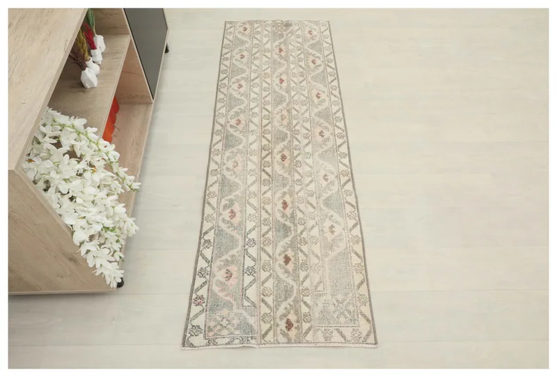 Full top view of the beige and gray tribal geometric runner rug on a white floor