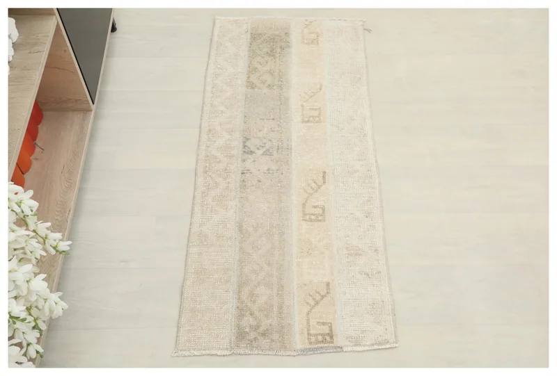 Full top view of a beige patchwork area rug with geometric patterns on a white background