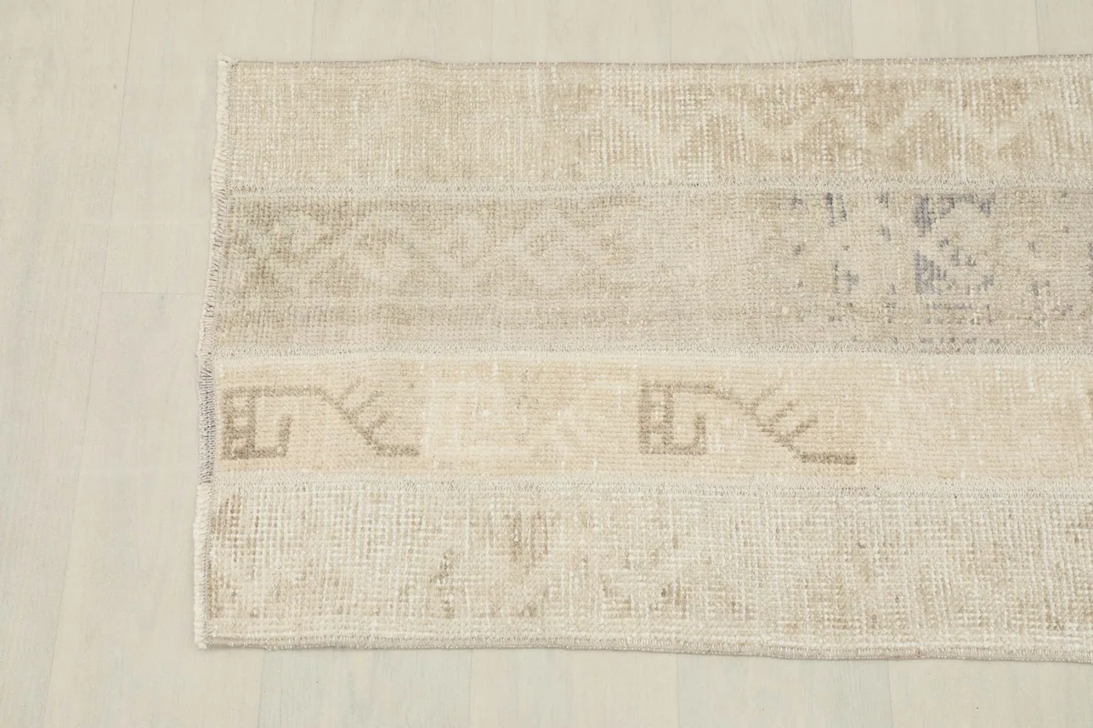 Detailed view of the rug's geometric and tribal motifs in various shades of beige and gray