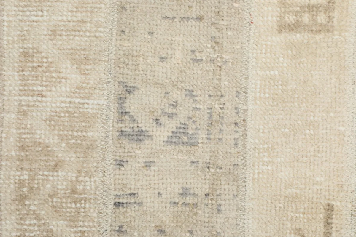 Macro detail of a gray and beige patch, revealing the hand-knotted wool texture and patina