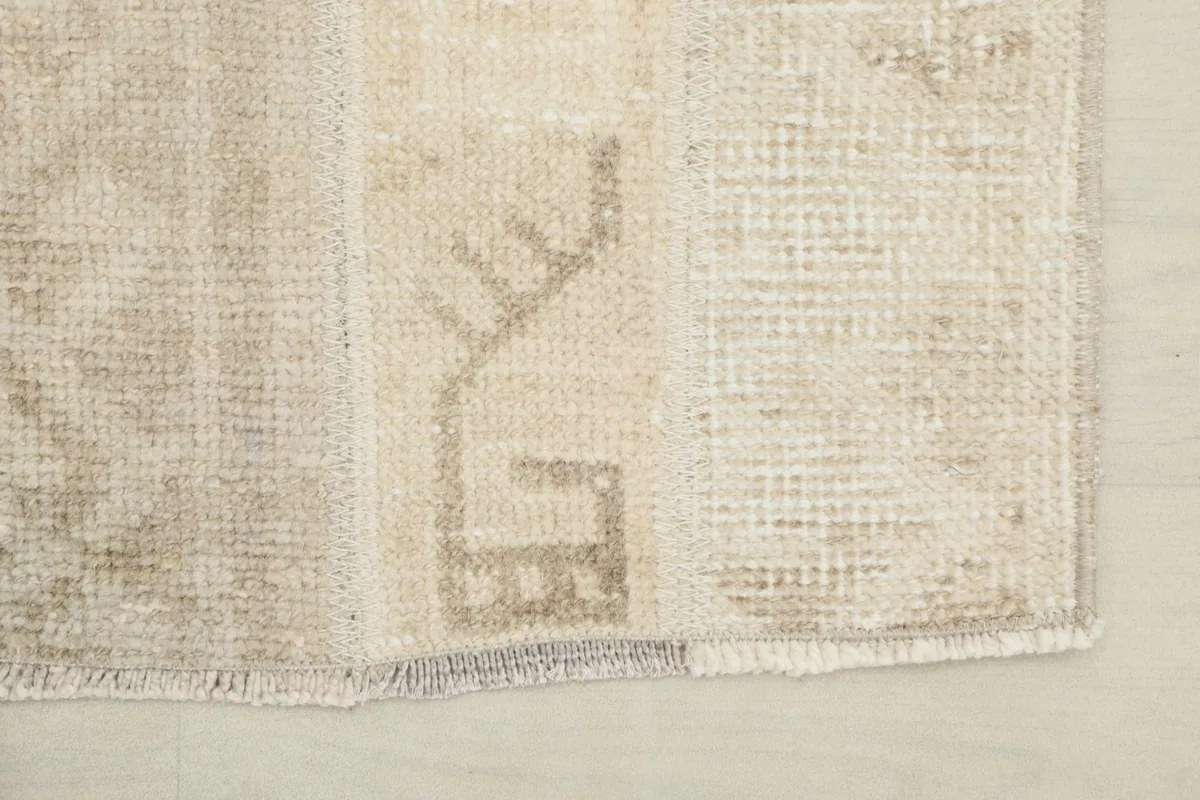 Close-up of the rug's end, showing the short, natural fringe and a geometric motif