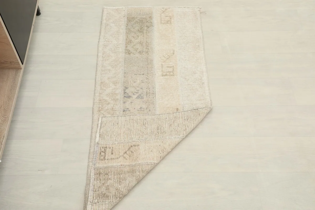 The beige patchwork rug partially folded, showing its flexibility and full length