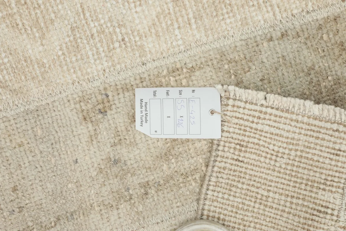 Close-up of the rug's corner with a product tag, showing the wool texture and hand-knotted detail