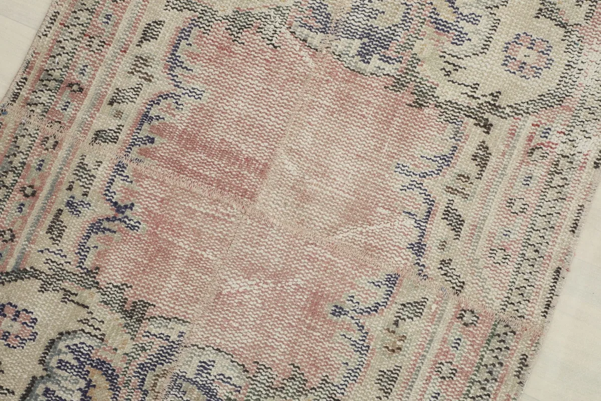 Detail view of the central faded rose field, showing wear and texture