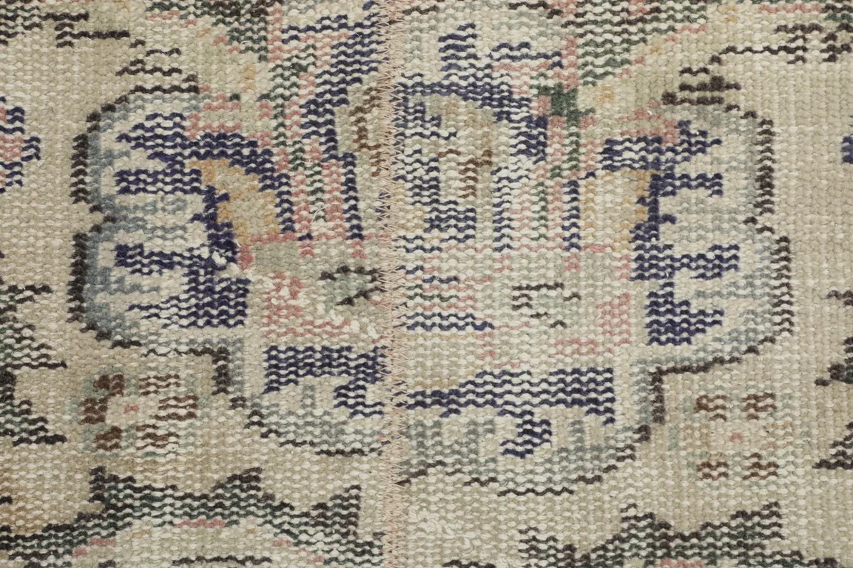 Close-up of the hand-knotted wool pile and intricate navy and beige motifs