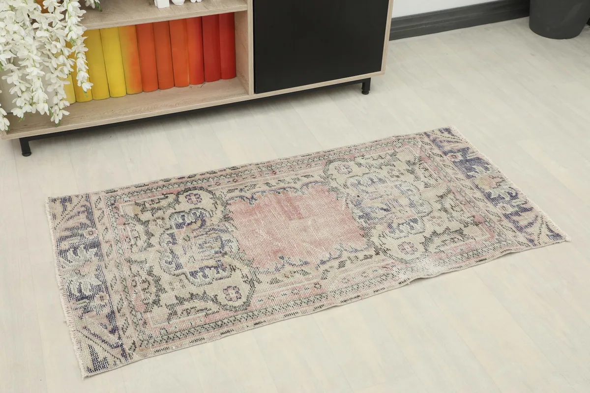 Overhead view of the vintage rose rug, showing its faded colors and geometric pattern