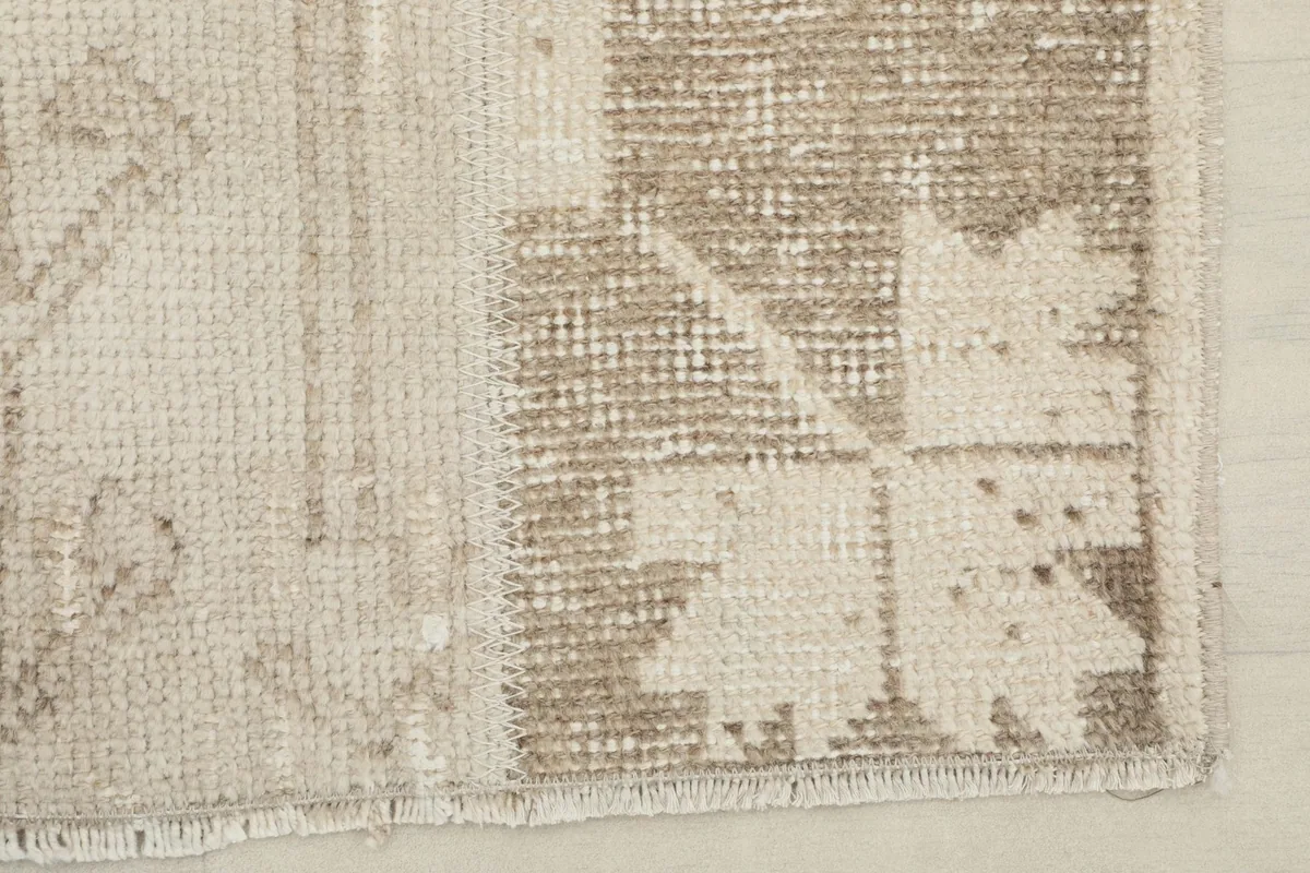 Corner detail of the rug showing the edge finish and vintage wear on the tan areas