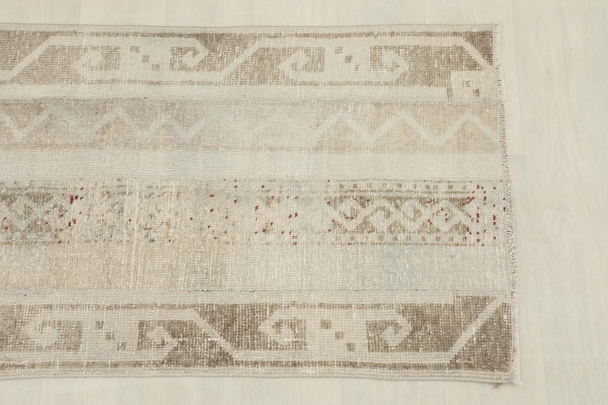 Overhead close-up of one end of the rug, highlighting the beige and tan geometric border designs.