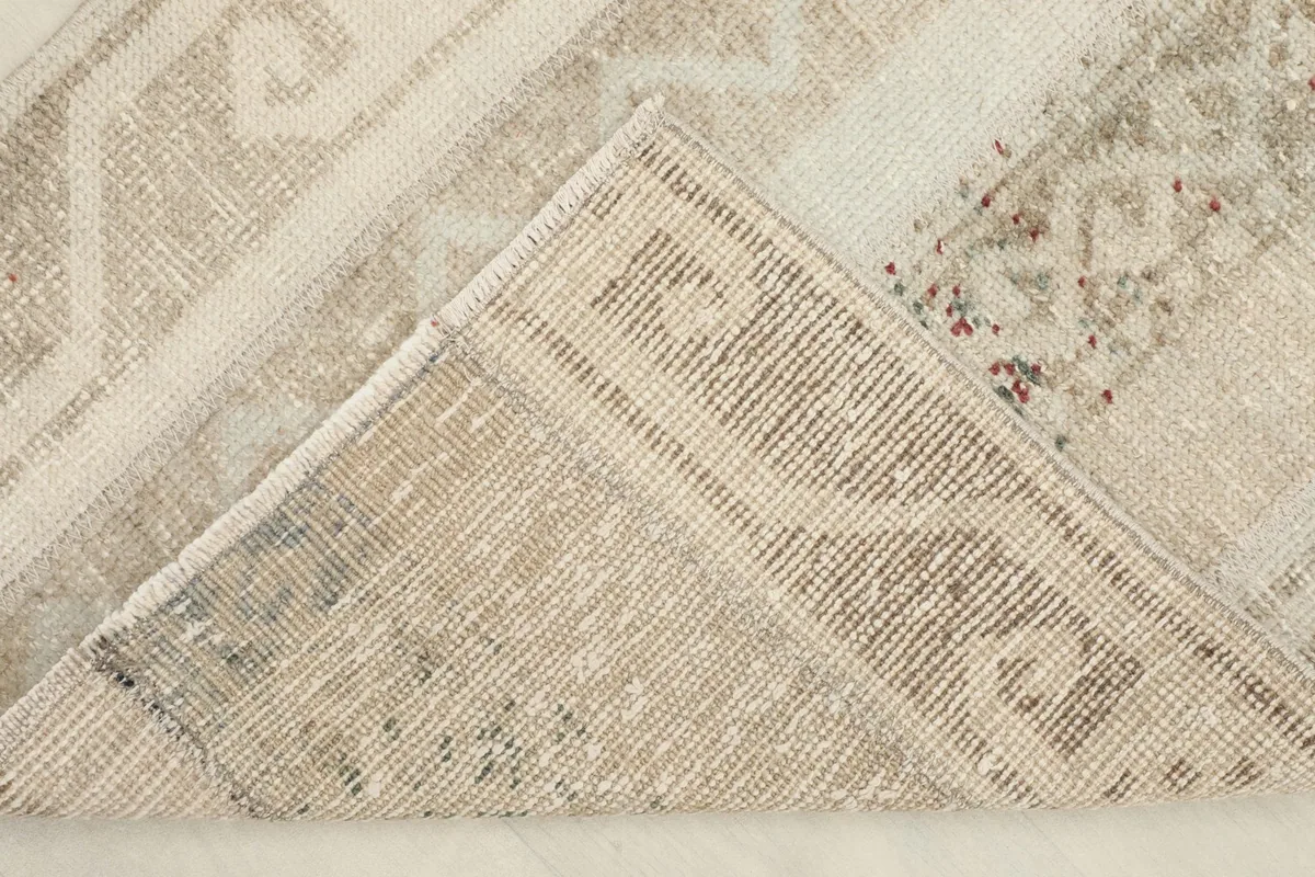 Corner folded back to show the reverse side of the hand-knotted wool pile on cotton foundation.