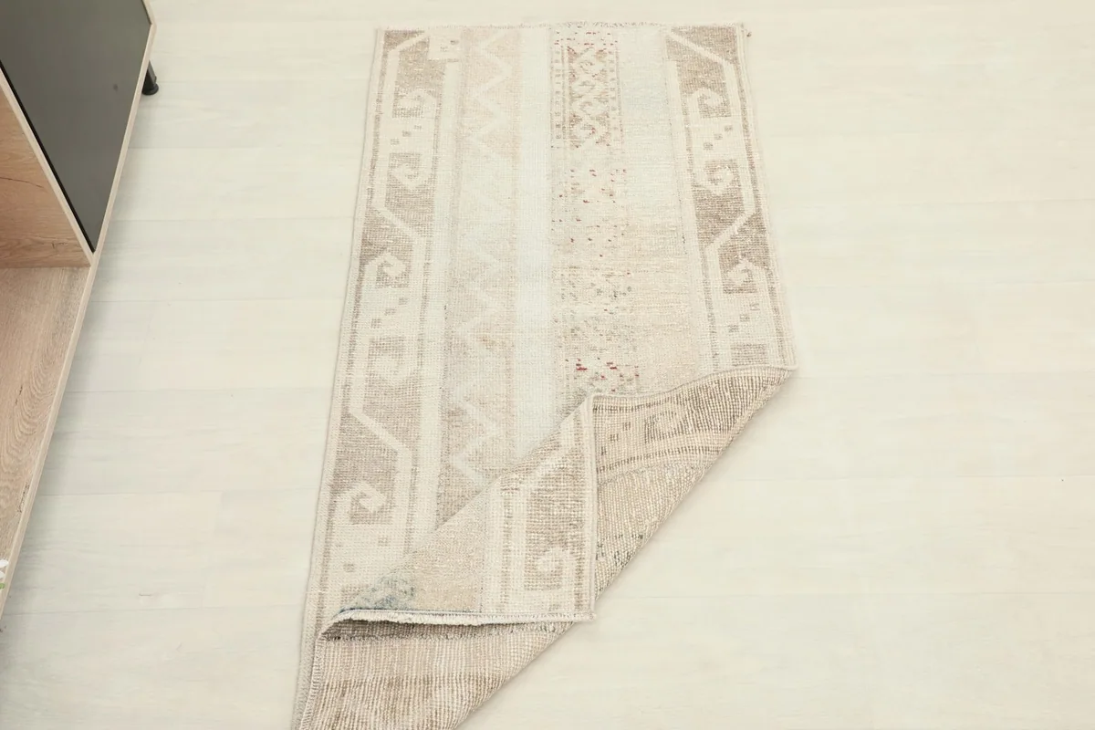 Full view of the rug with one corner folded, demonstrating its flexibility and vintage character.