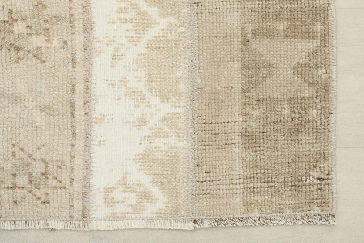 View of the rug's end with subtle fringe and the distressed texture of the pile