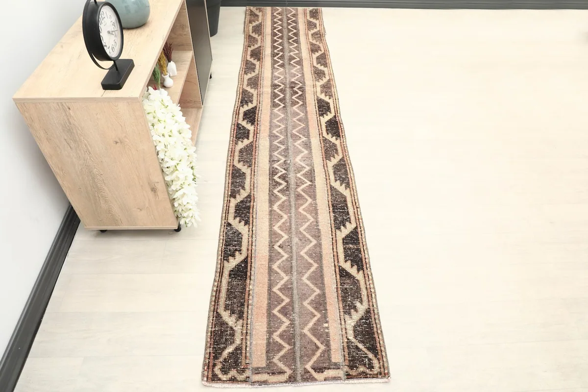 The long runner rug laid out in a hallway with minimalist furniture, showcasing its scale