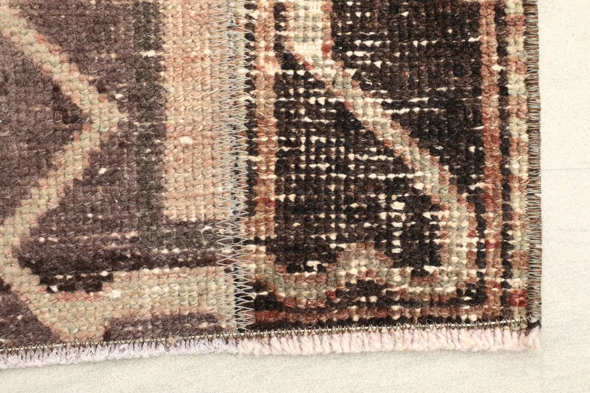 Close-up of the rug's end, showing a dark brown geometric pattern and subtle fringe