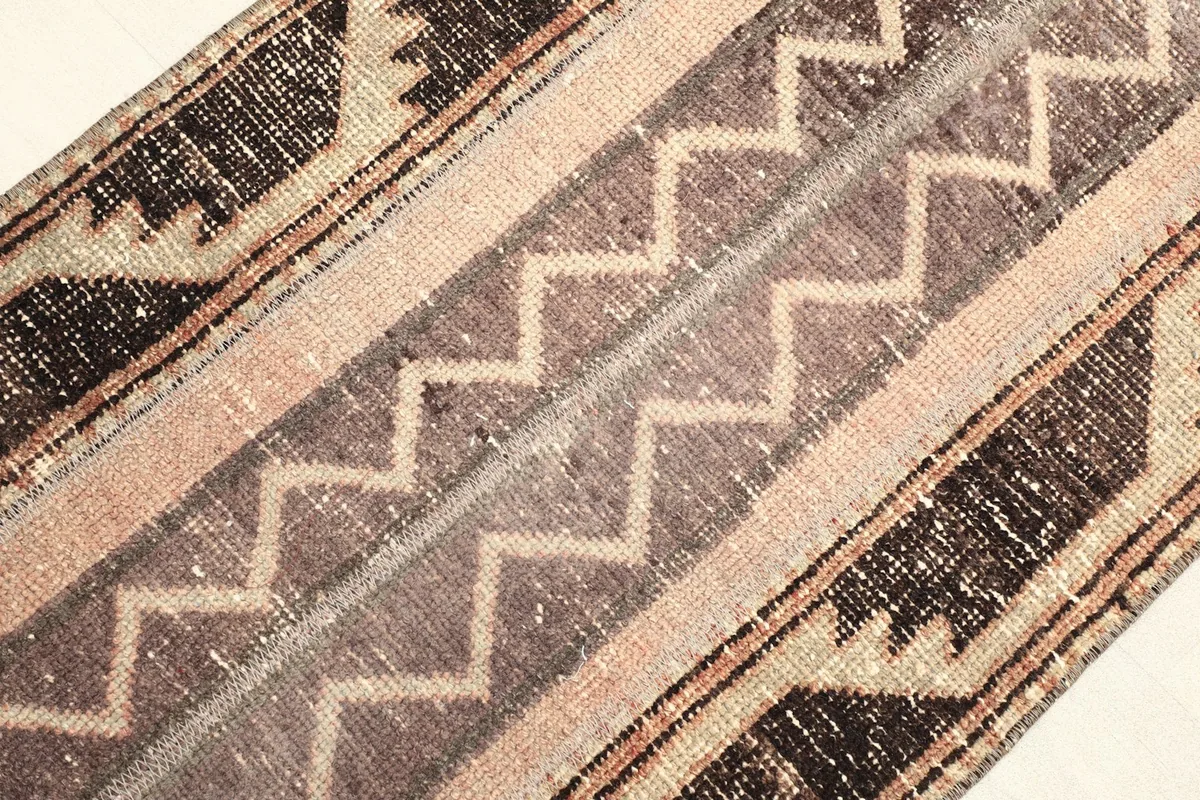Detailed view of the central section with beige and brown zigzag patterns and worn pile