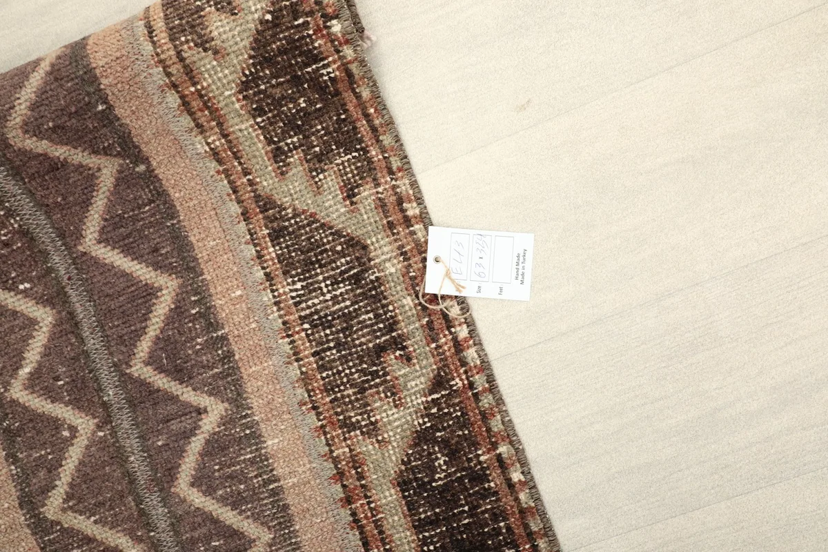 Close-up of the rug's edge, showing the hand-knotted construction and a small product tag