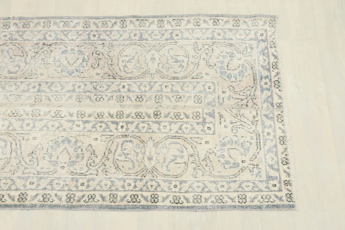 Close-up detail of the rug's border and central design, highlighting the blue floral patterns on an ivory field.