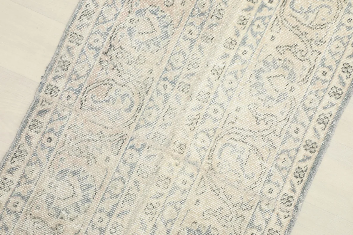 Overhead detail shot of the rug's central design, emphasizing the distressed texture and faded blue patterns.