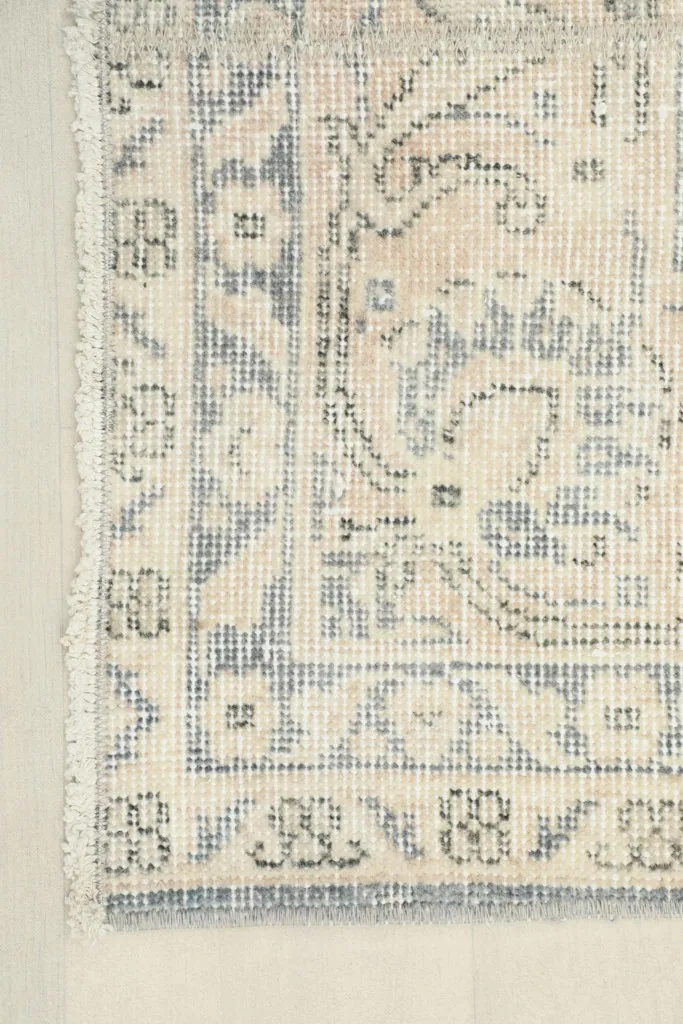 Close-up of the rug's edge and fringe, showcasing the hand-finished details and the ivory and blue colors.