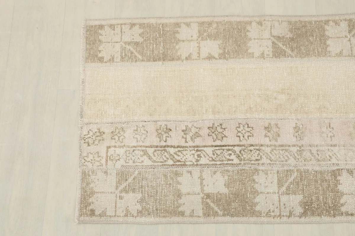 Detailed view of the rug's left side, showing a tan panel with a leaf-like geometric motif.