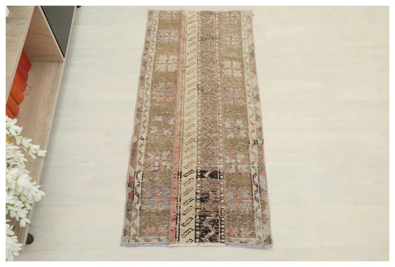 Full overhead view of the 1'10" x 4'1" brown geometric patchwork rug on a white floor.