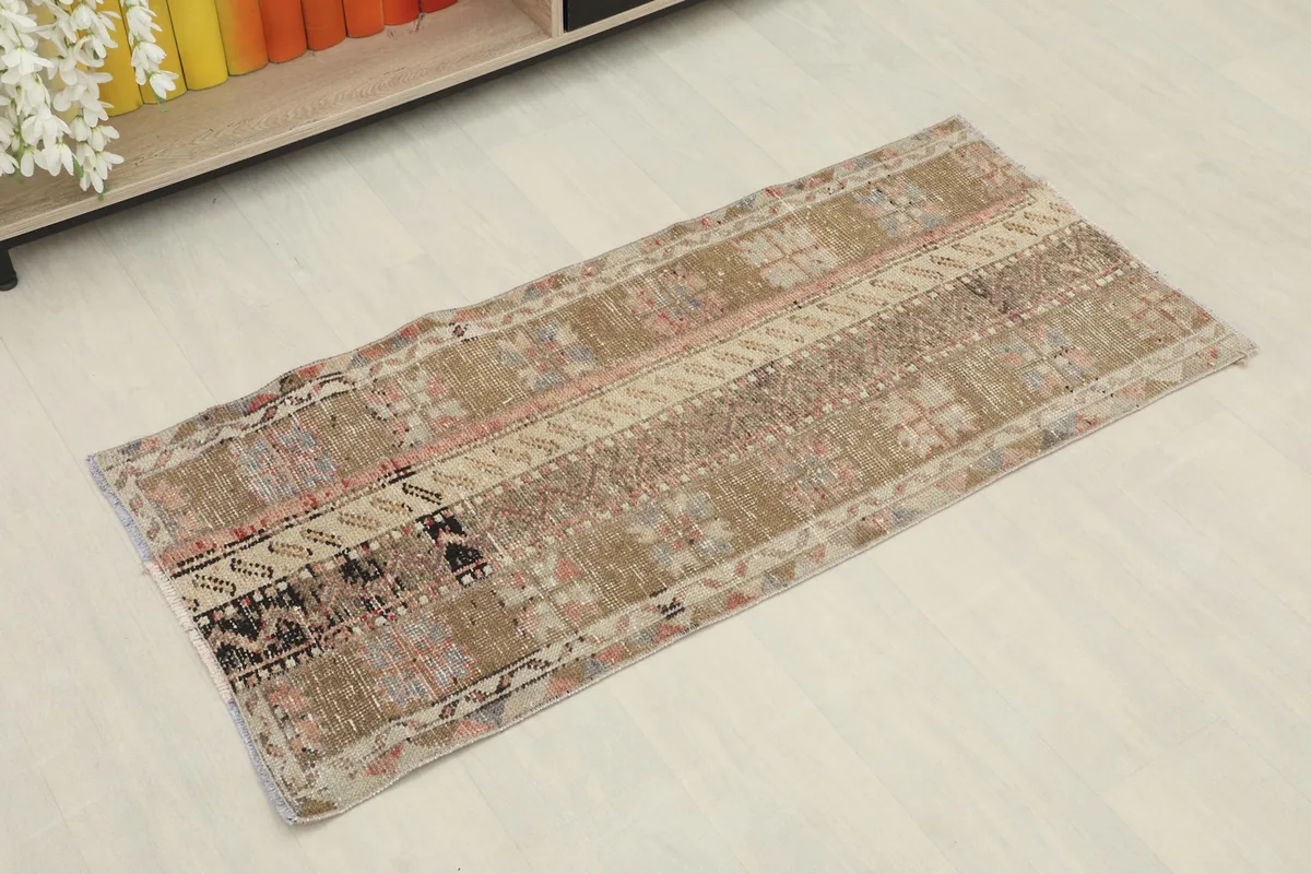 Angled view of the vintage Anatolian rug, showcasing its brown, beige, pink, and black patterns.