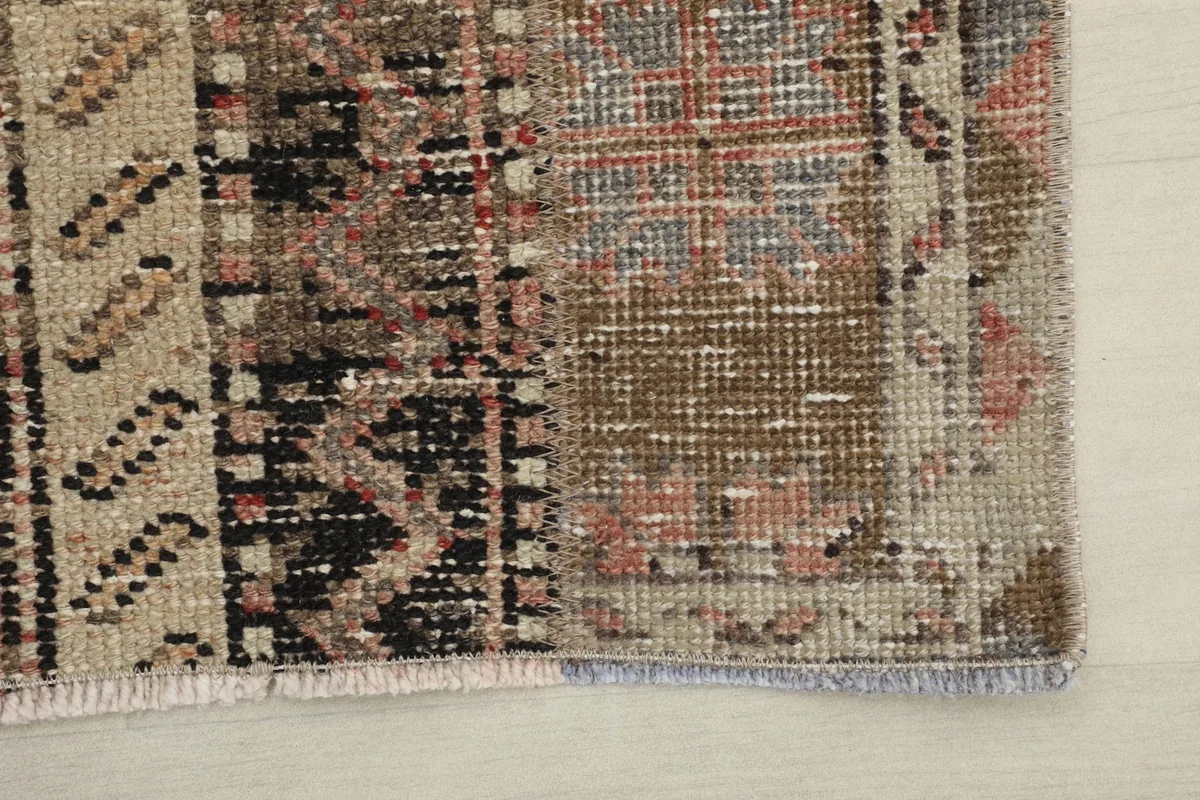 Detail of the rug's edge, showing the finished binding and a section of the geometric pattern.