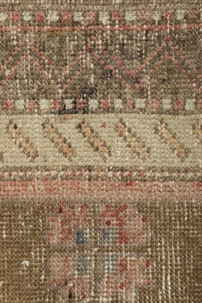 Close-up view of the rug's low wool pile, showing the intricate knotting and distressed texture.