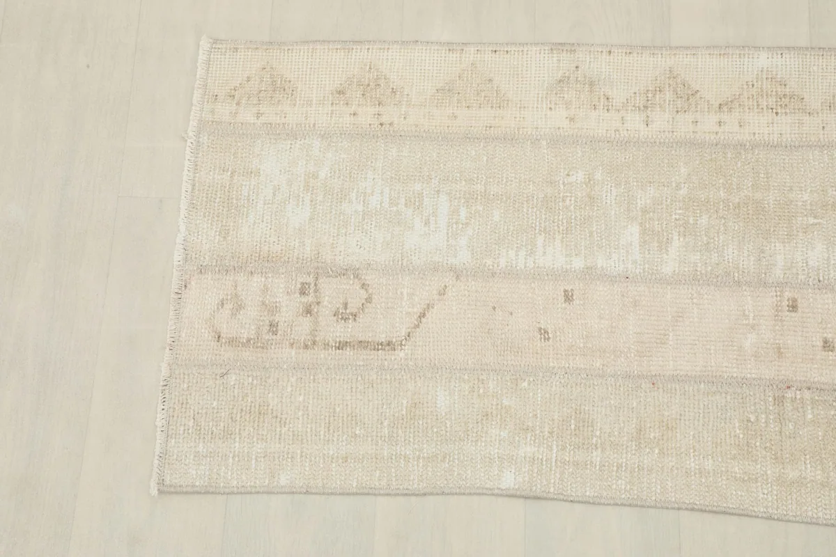 Detailed view of the rug's tribal geometric patterns on the cream field