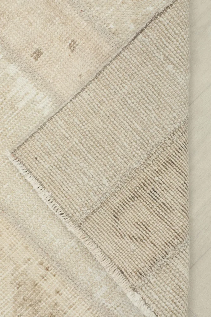 Corner of the rug folded to reveal the cotton foundation and hand-knotted construction