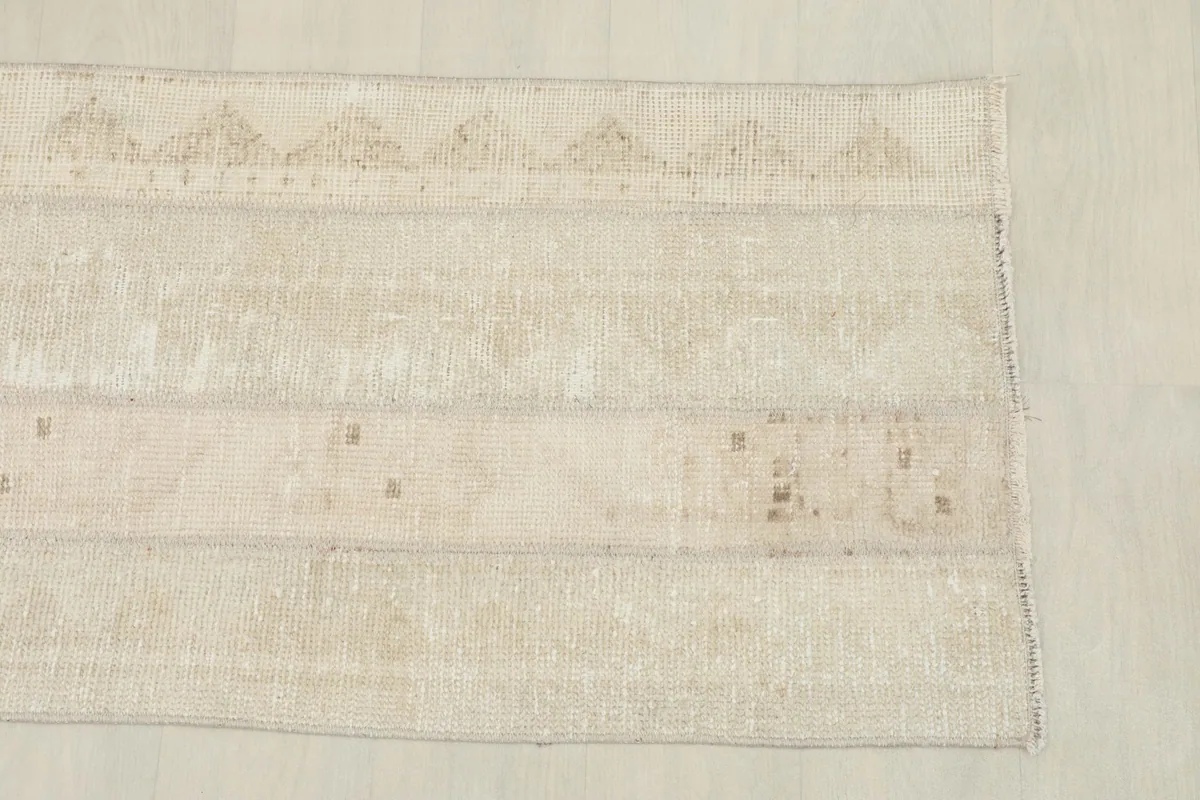 Close overhead view of the rug's patterns and texture, highlighting the beige tones