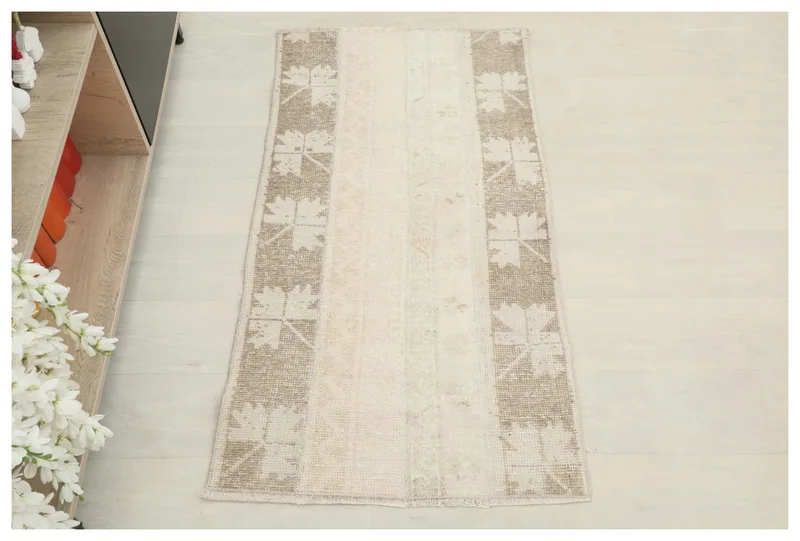 Full overhead view of the beige and tan geometric panel vintage Anatolian rug on a white floor.