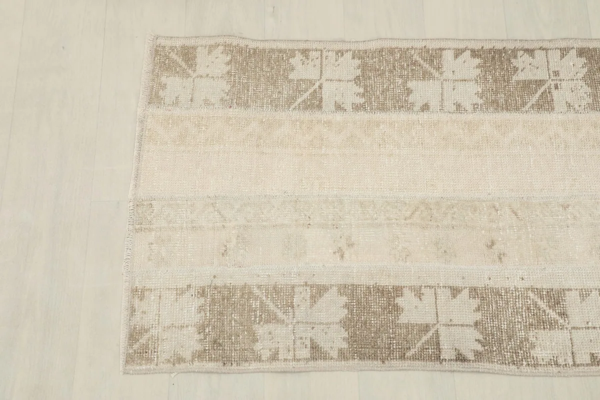Detailed view of the rug's border and central beige field with subtle patterns.