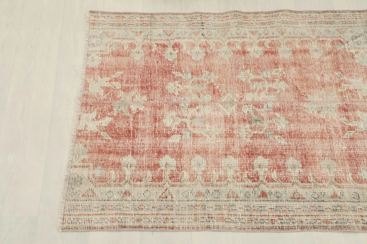 Close-up of the rug's surface, showing the faded rose field and intricate beige floral motifs.