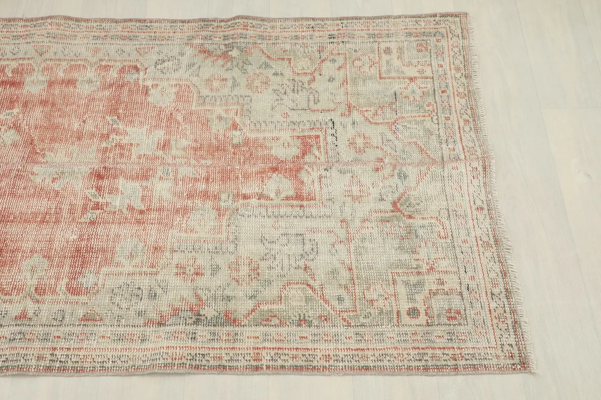 Detailed view of the rug's border design, featuring geometric patterns in beige and subtle gray tones.