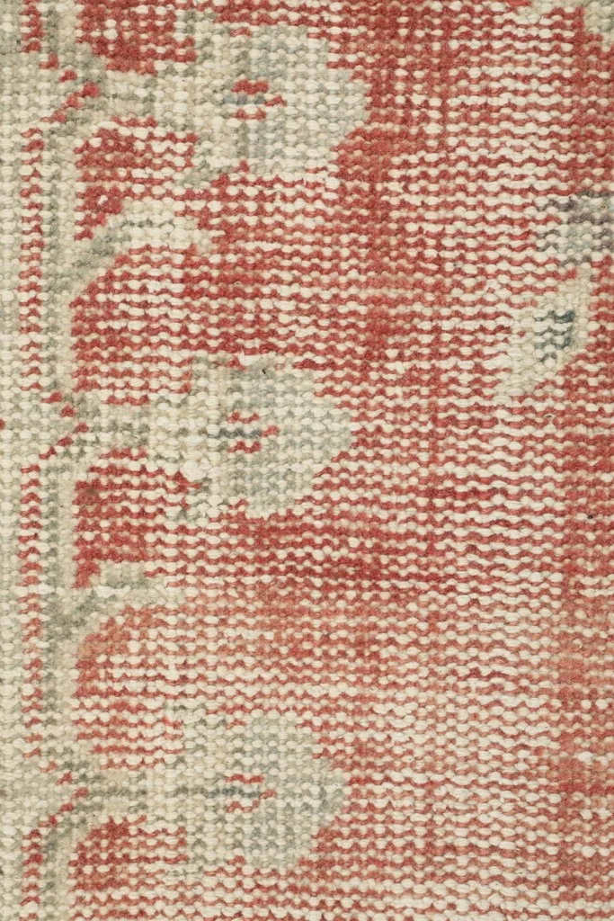 Extreme close-up of the low wool pile, showing the texture and color variations of the rose and beige threads.