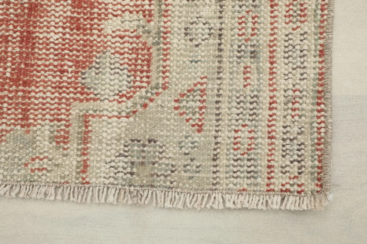 Close-up of the rug corner, showing the natural cotton foundation fringe and the low pile texture.