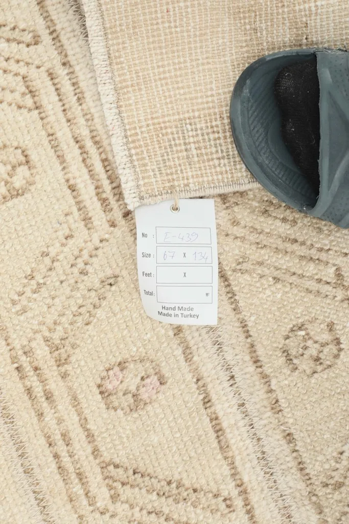 Tag showing rug dimensions and origin, beside a slipper for scale
