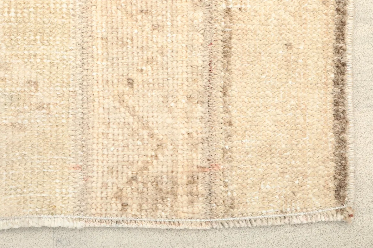 Close-up detail of the hand-knotted wool pile and subtle color variations of the beige rug