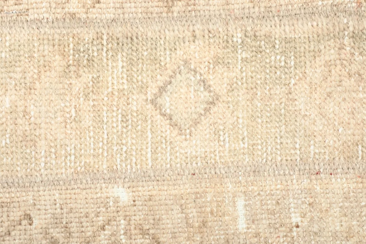 Detailed view of a diamond-shaped geometric motif within the beige and tan rug's pattern