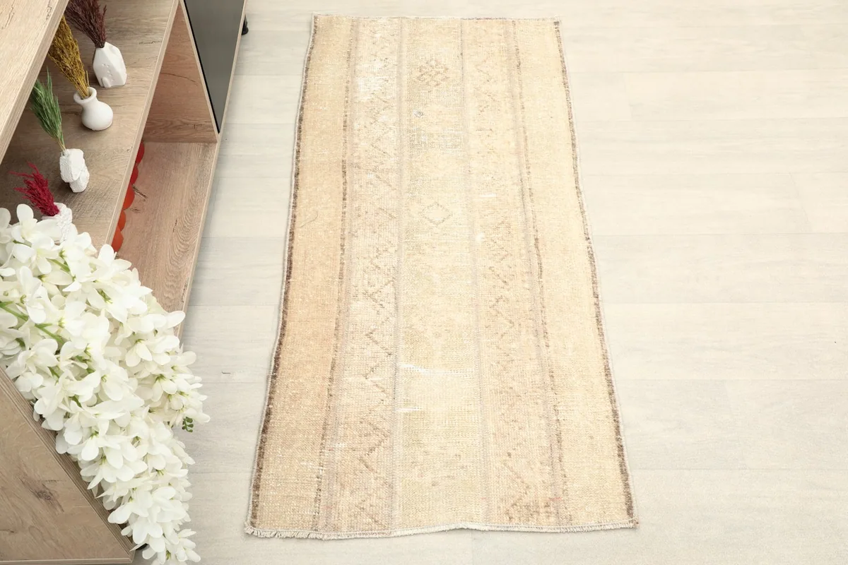 Overhead view of the beige and tan vintage rug, showing its full length and striped design