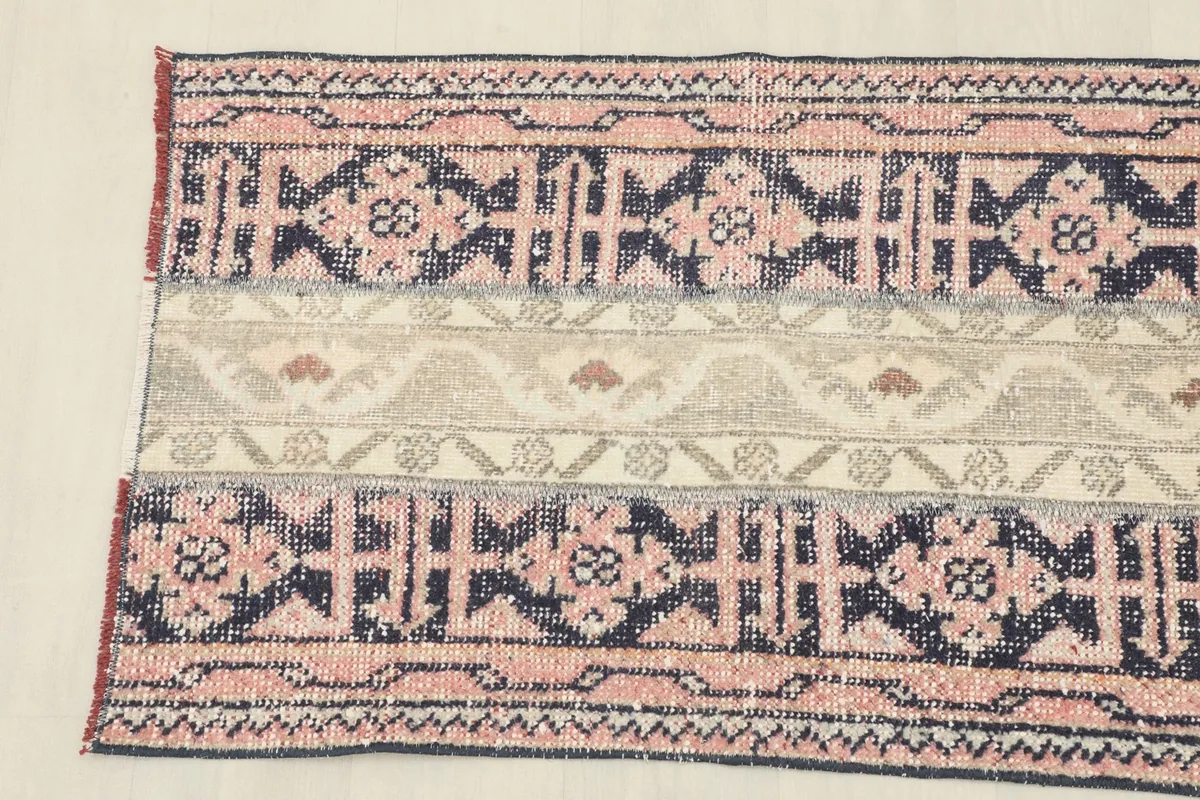Detailed view of the rose and navy geometric patterns, and the beige central stripe.