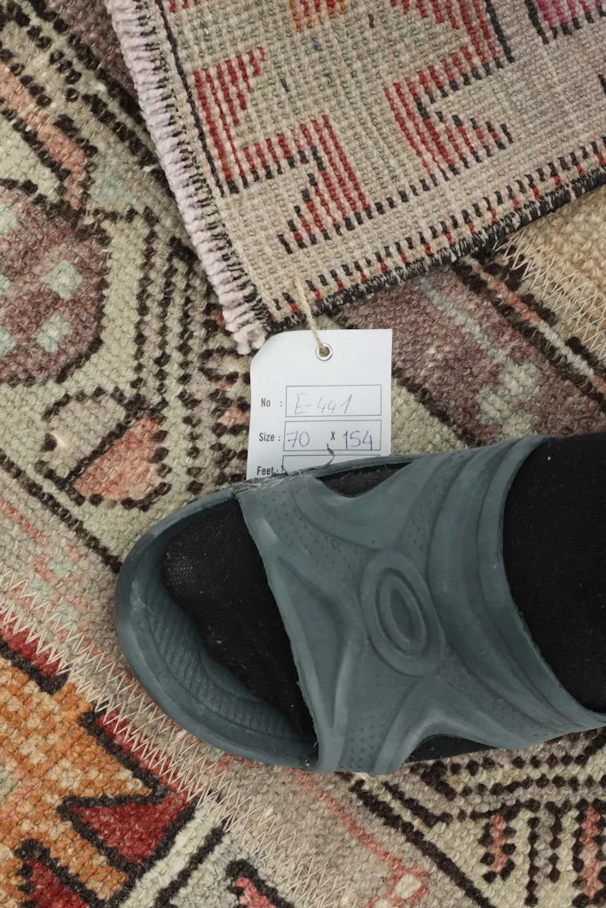 Close-up of the rug with a size tag and a shoe for scale, highlighting the texture