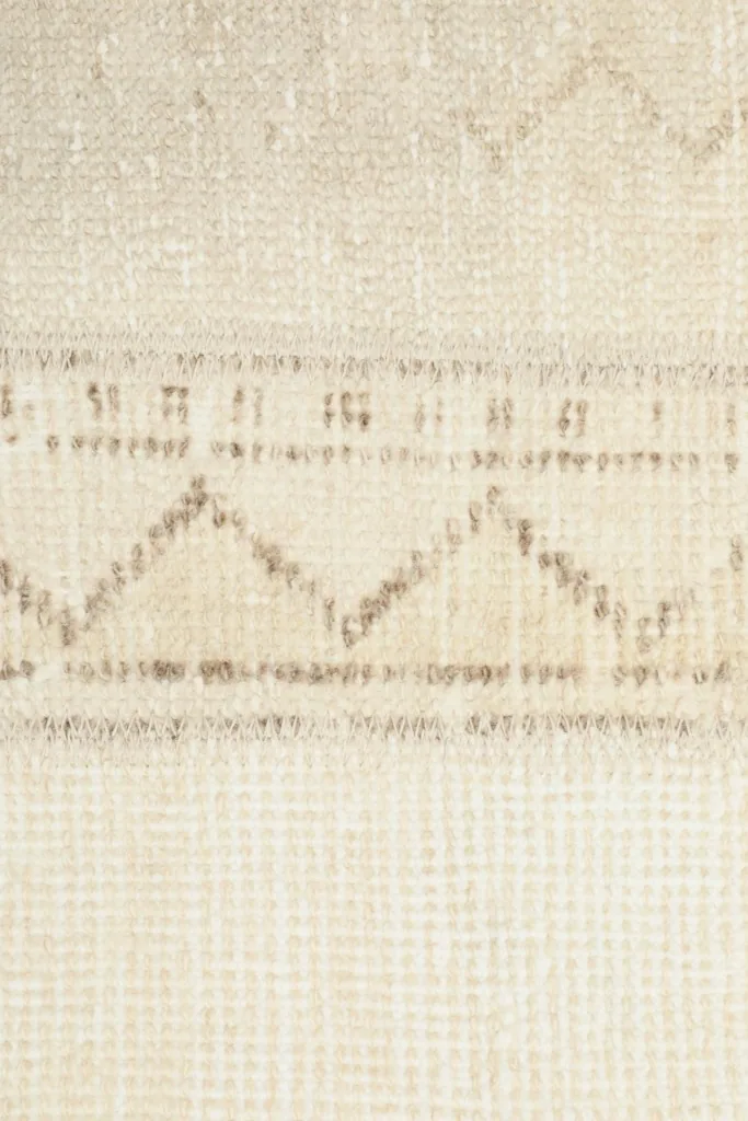 Close-up of a specific geometric motif in tan on a beige panel