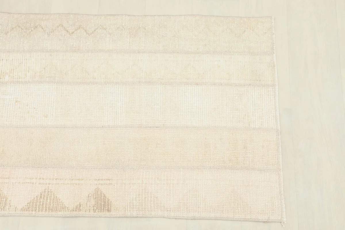 Close overhead view highlighting the varied beige and tan panels of the rug