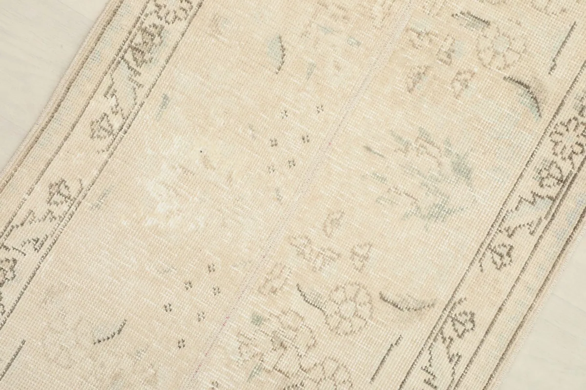 Detailed shot of the wool pile and the subtle floral and geometric motifs in ivory, beige, and gray