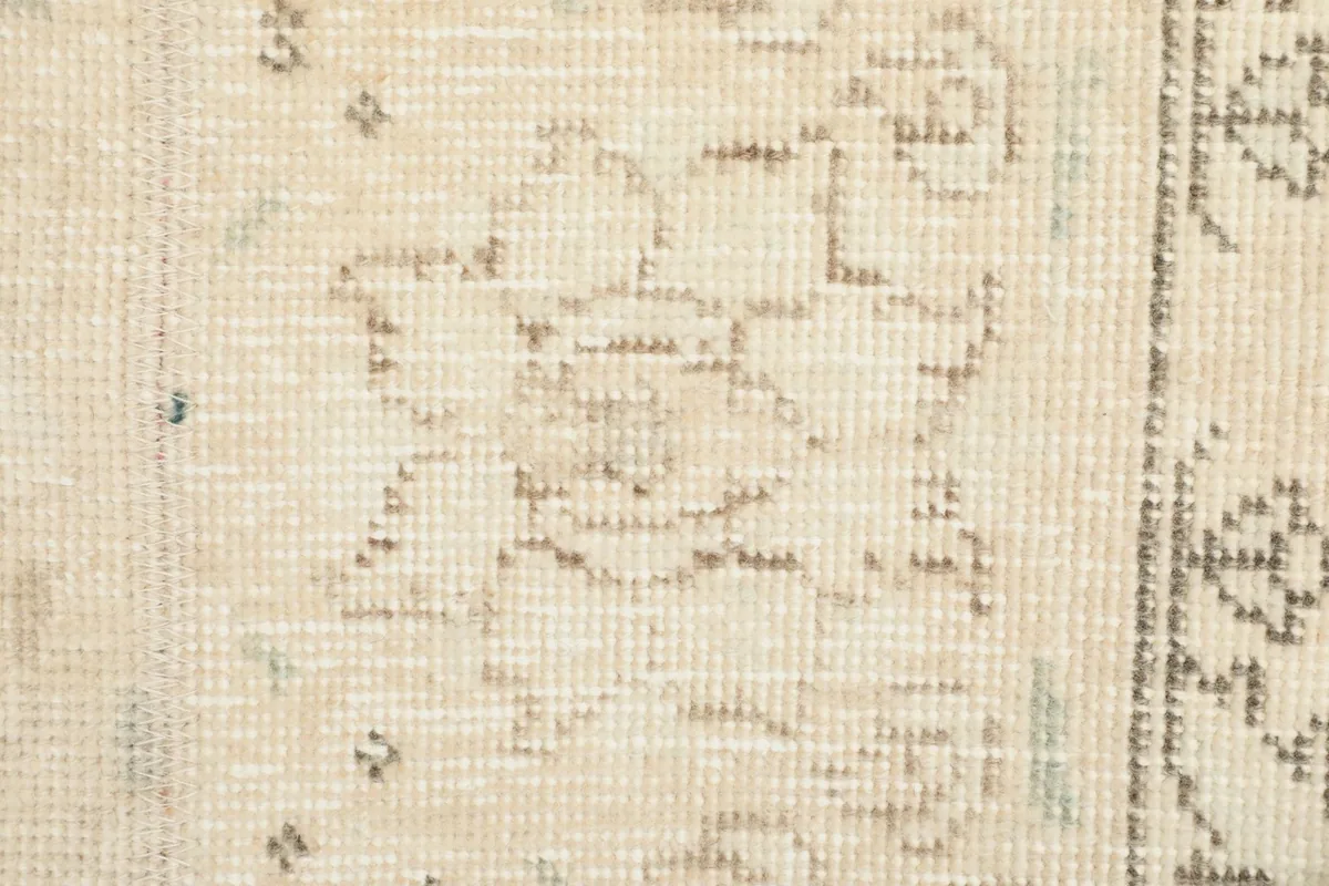 Extreme close-up of a specific floral motif within the rug, revealing the hand-knotted texture